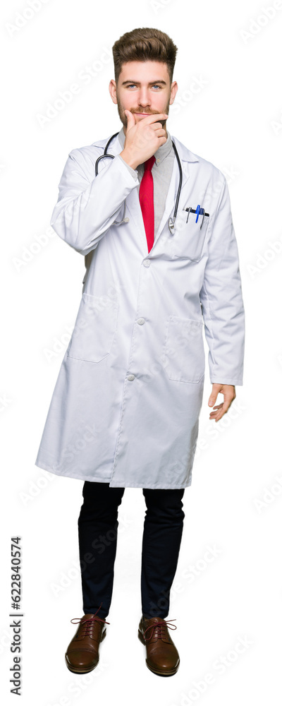Young handsome doctor man wearing medical coat looking confident at the camera with smile with crossed arms and hand raised on chin. Thinking positive. Young handsome doctor man wearing medical coat looking confident at the camera with smile with crossed arms and hand raised on chin. Thinking positive.