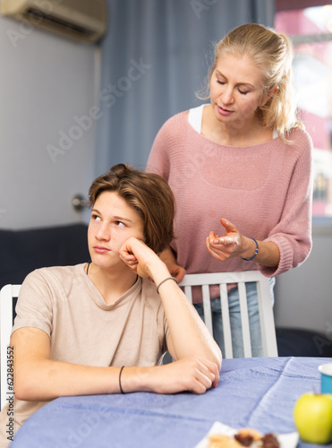 Worried mother trying to talk to upset teenage son at home. Concept of communication difficulties in adolescence