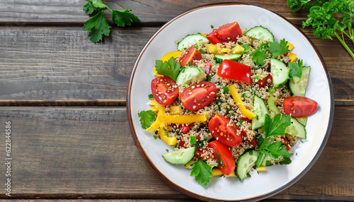 Fresh healthy salad with quinoa, colorful tomatoes, sweet pepper, cucumber and parsley on wooden background top view. Food and health. Superfood meal. Space for text.