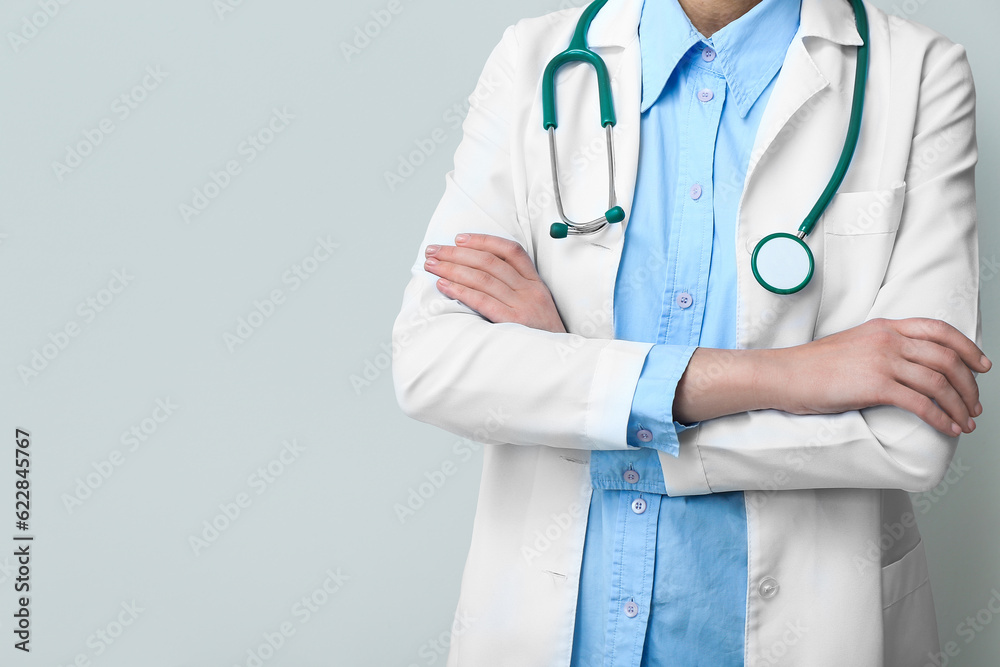 Female doctor in white coat with stethoscope on grey background Female doctor in white coat with stethoscope on grey background
