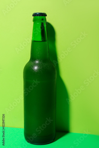 Bottle of cold beer on green background