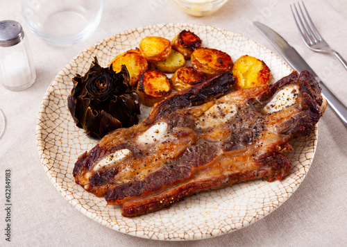 Popular Spanish dish of grilled beef steak Churrasco, potatoes and artichokes
