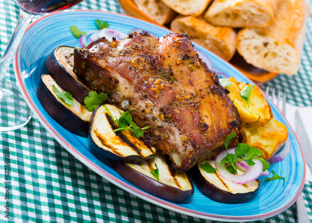 Juicy barbecue rack of pork served with grilled eggplant, potato and onion rings