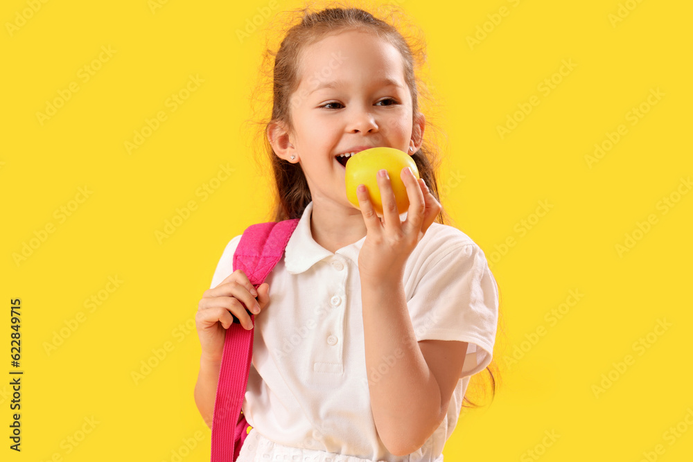 Little schoolgirl with apple on yellow background Little schoolgirl with apple on yellow background