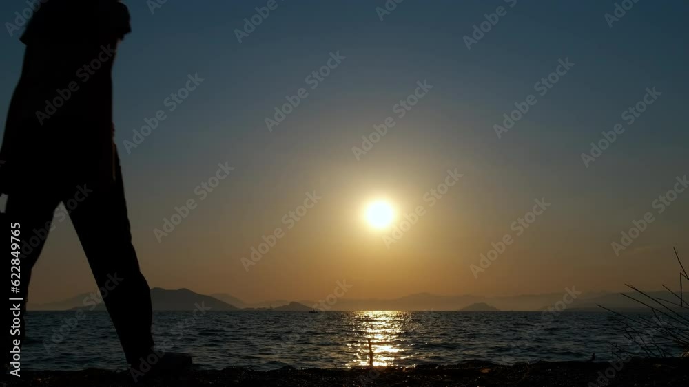 Teen silhouette enjoy sea walk. A young tourist silhouette hold her backpack and have a sea promenade during nightfall. Teen silhouette enjoy sea walk. A young tourist silhouette hold her backpack and have a sea promenade during nightfall.