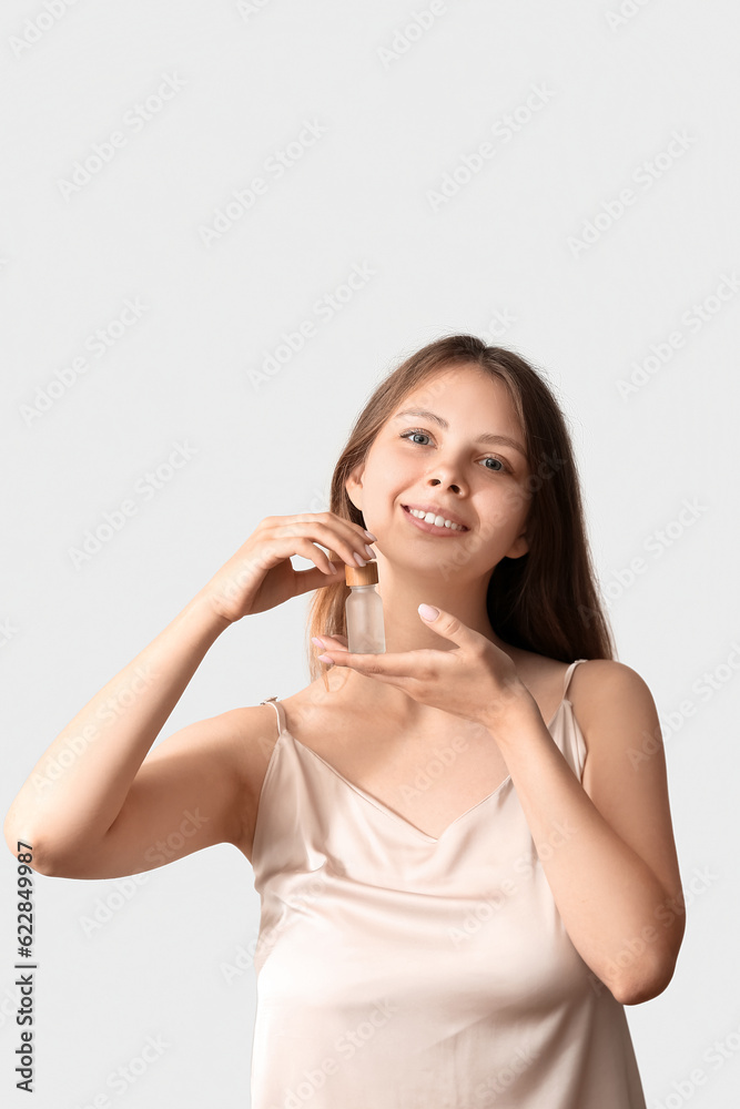Pretty young woman with cosmetic oil on light background Pretty young woman with cosmetic oil on light background