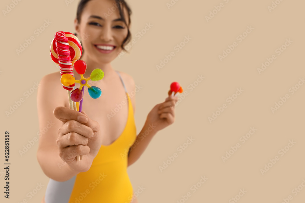 Young woman in swimsuit with lollipops on beige background, closeup Young woman in swimsuit with lollipops on beige background, closeup