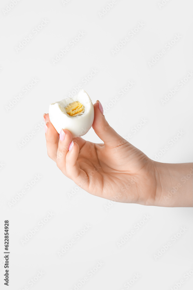 Female hand holding boiled chicken egg on white background Female hand holding boiled chicken egg on white background
