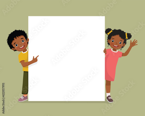 Papier peint Cute African kids little boy and girl standing behind empty banner peeking and p