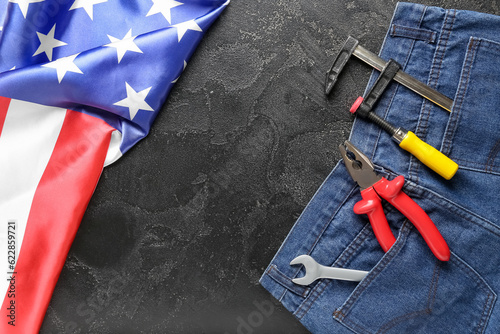 Composition with jeans, different tools and USA flag on black background. Labor Day celebration