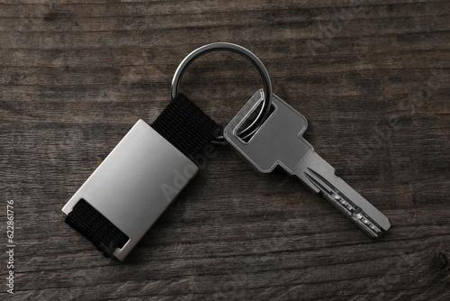 Key with metallic keychain on wooden background, top view