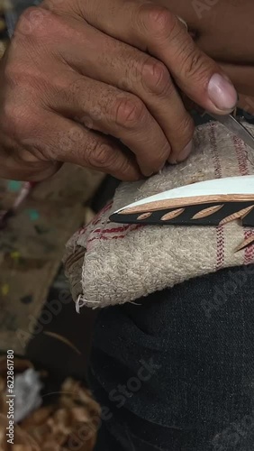 on the street man with beard of Indian appearance first people of Canada locals carving feather Poor people poverty close-up details of his work sawdust hands creativity crafting Vancouver Canada 2023 photo