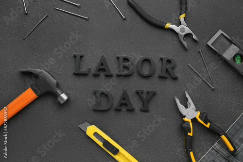 Different tools and text LABOR DAY on black grunge background