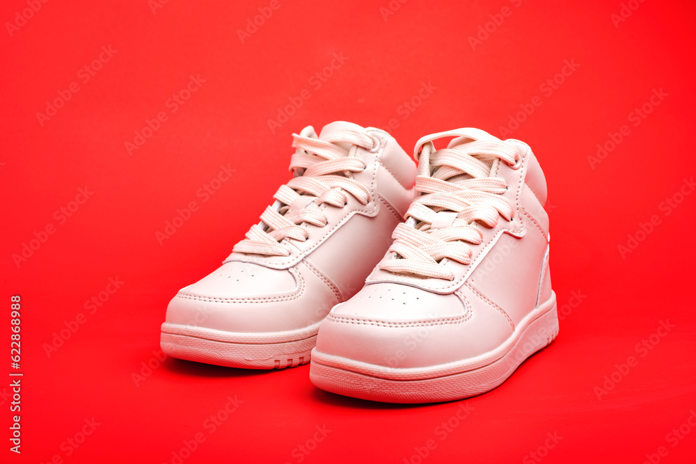 children's high sneakers on red background close-up.