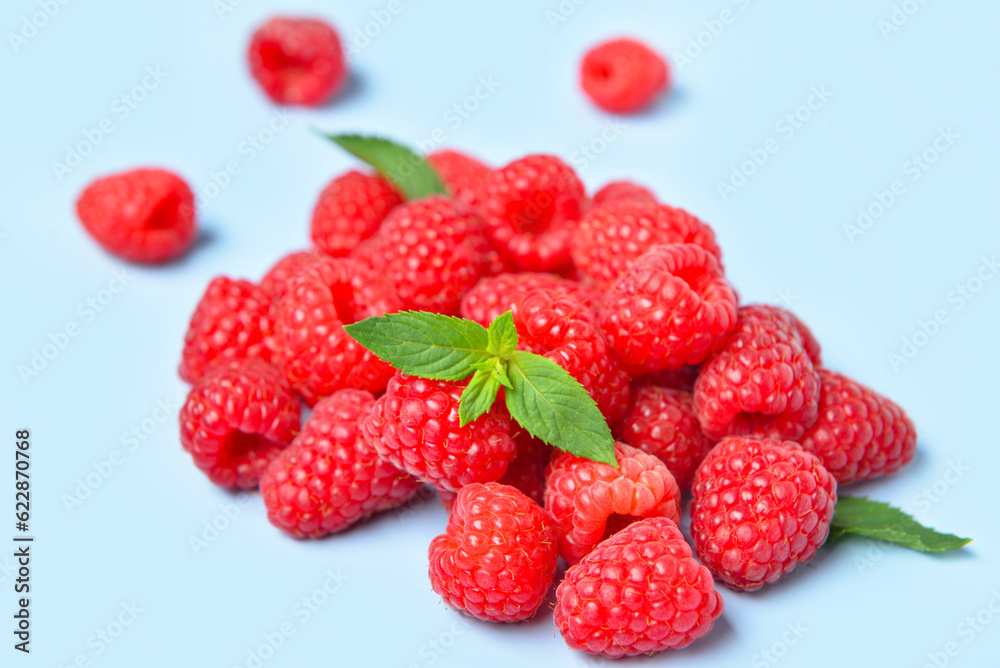 Heap of fresh raspberries and mint on blue background Heap of fresh raspberries and mint on blue background