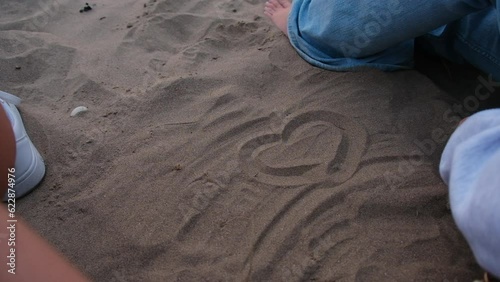 One Person drawing a heart in the sand with their finger. photo