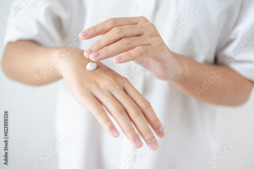 Asian woman hands applying skin cream on hands and arms for healthy skin.