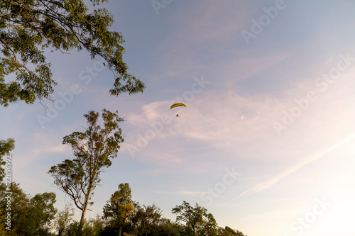 Person flying on a paraglider at sunset.