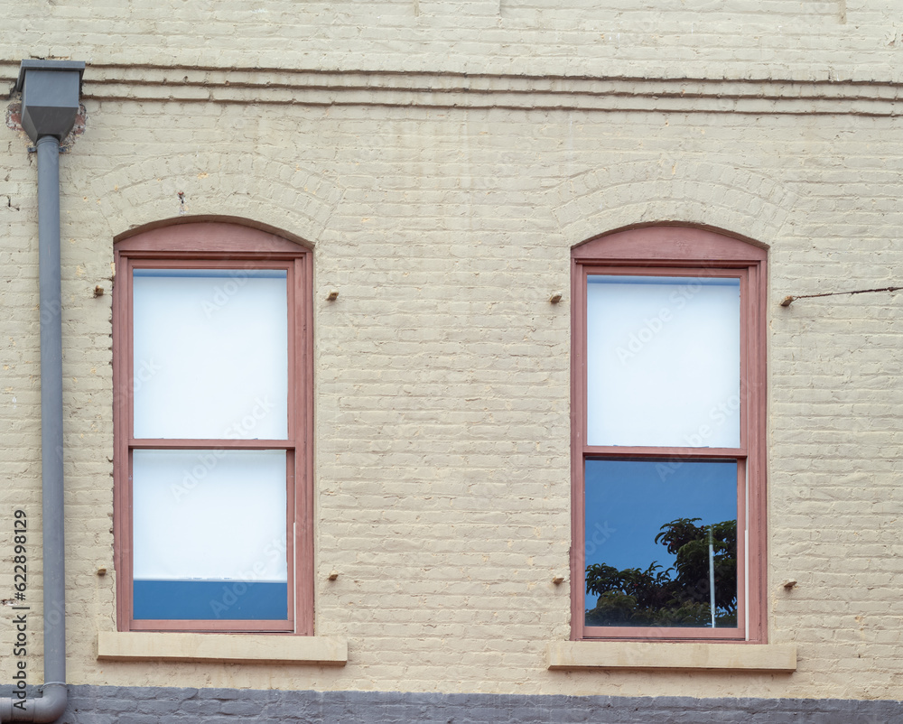 Beige Building with Red arched Windows and a Reflection.