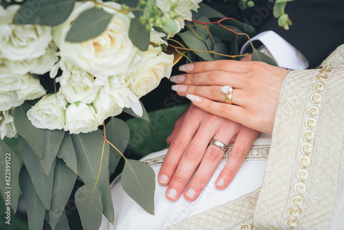 Close Up of Bride and Groom Holding Hands with Wedding Rings and White Flowers – Muslim Wedding, Marriage Ceremony, Love, Romance, Commitment, Engagement, Bridal Jewelry, Islamic Culture, Marriage