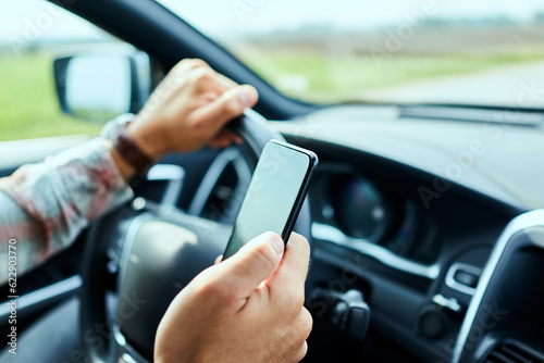 Man using a smart phone while driving a car on the road