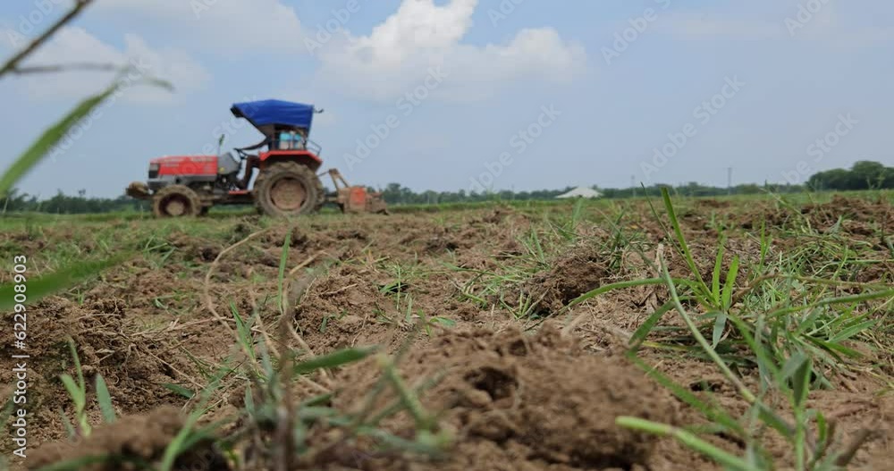 Defocused view of Unidentified farmer with tractor preparing land for sowing with tractor and cultivator, Odisha, India Defocused view of Unidentified farmer with tractor preparing land for sowing with tractor and cultivator, Odisha, India