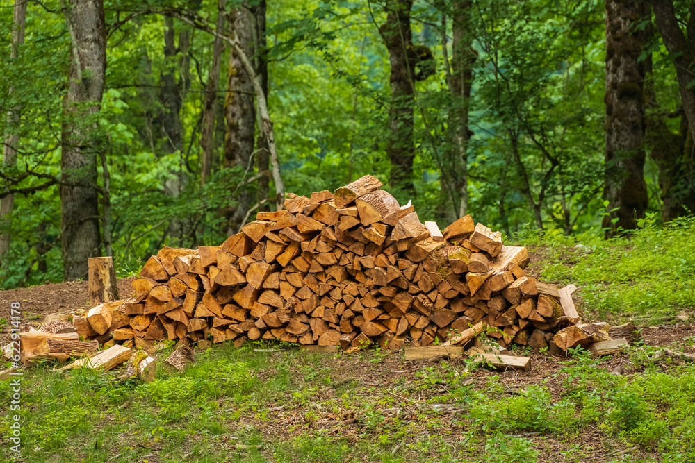 A pile of stacked firewood, prepared for heating the house, Chopped firewood on a stack. Pile of firewood loggs. A pile of stacked firewood, prepared for heating the house, Chopped firewood on a stack. Pile of firewood loggs.
