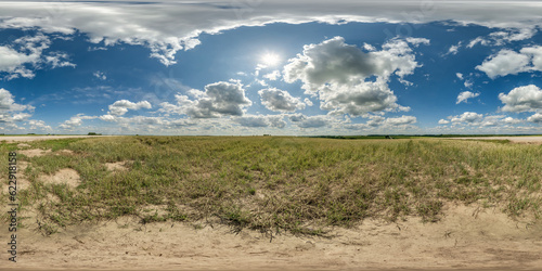 360 hdri panorama among dry farming field with clouds on blue sky with sun in hot day in equirectangular spherical seamless projection, use as sky replacement, game development as skybox or VR content