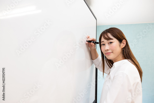ホワイトボードに書き込む女性　横