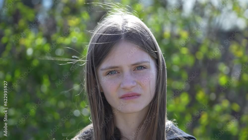 Portrait of a gloomy pouting cute girl with blond hair and freckles looking at the camera, frowning offended or insulted, standing bothered over nature background, close up Portrait of a gloomy pouting cute girl with blond hair and freckles looking at the camera, frowning offended or insulted, standing bothered over nature background, close up