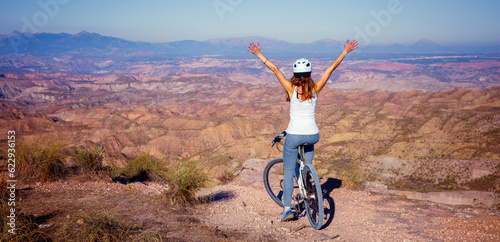 Woman with open arms in bike- active woman, adventure or sport concept