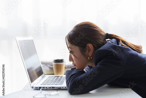 職場のデスクでパソコンを見て暗い表情をする女性 photo