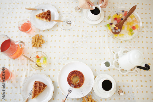 お菓子が並べられたテーブルとコーヒーを飲む女性 photo