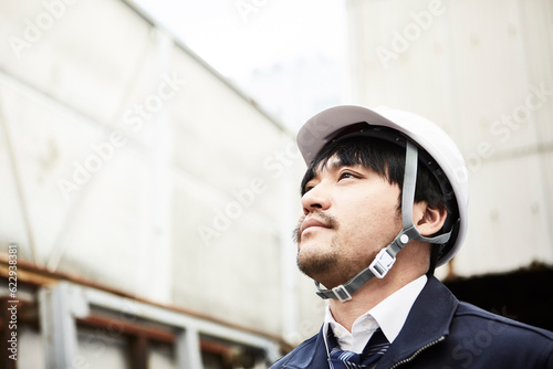 上を見上げている作業服とヘルメットの男性 photo