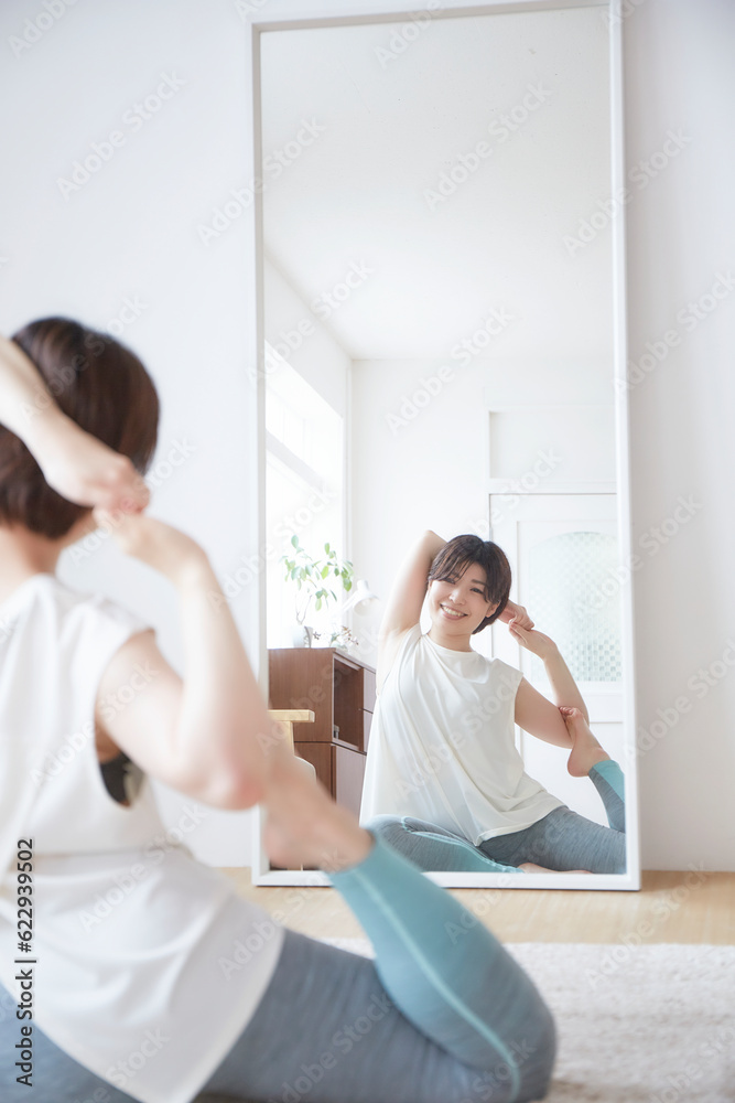 鏡に向かってストレッチをする女性 鏡に向かってストレッチをする女性