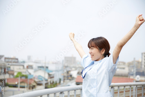 屋上で伸びをする女性の看護師 photo
