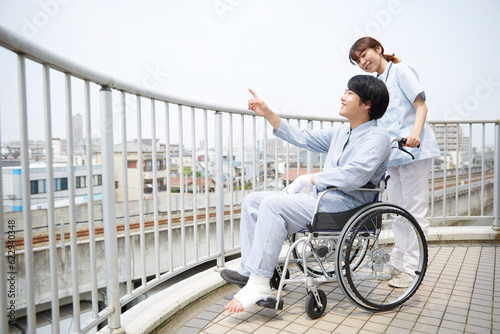 屋上で車椅子の患者と話す女性の看護師