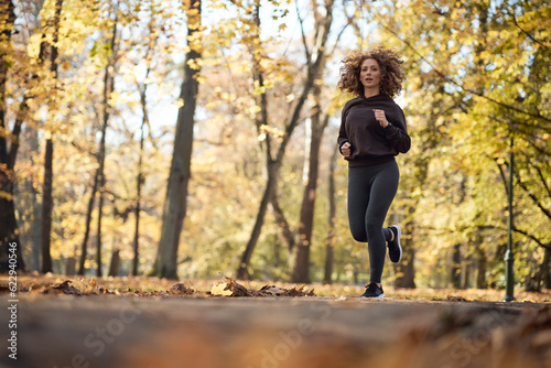 Wide shot of caucasian woman jogging in the park in the autumn