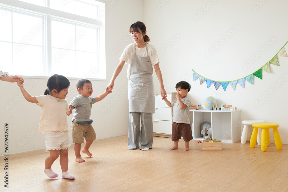 子供たちと手を繋ぐ女性の保育士 子供たちと手を繋ぐ女性の保育士