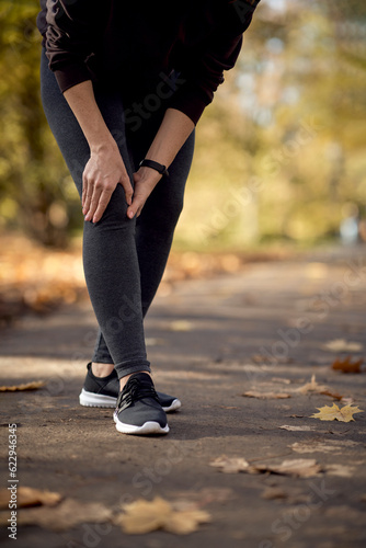Low section of woman feeling knee injury during jogging in the park © gpointstudio