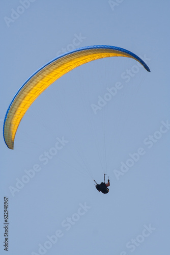 A man flies on paraplane. Clear blue sky. photo