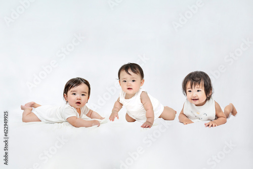 白背景の前でハイハイする3人の赤ちゃん
