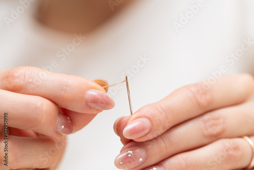 針に糸を通す女性の手元 photo