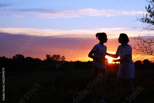 Silhouettes of mother and daughter against the sunset