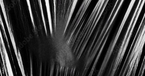 Visual effect of stretched plastic film texture against dark black background.