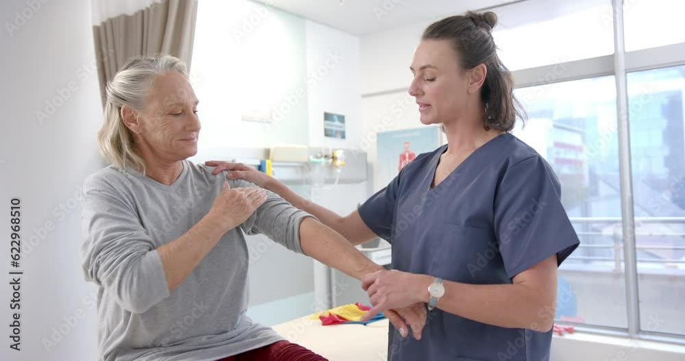 Caucasian female physiotherapist stretching hand of female senior patient at rehab center Caucasian female physiotherapist stretching hand of female senior patient at rehab center