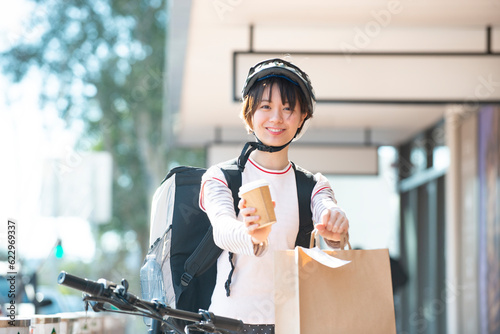 デリバリーの商品を差し出している配達員の女性 photo