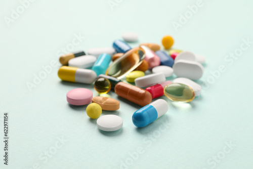 Pile of different pills on mint background, selective focus