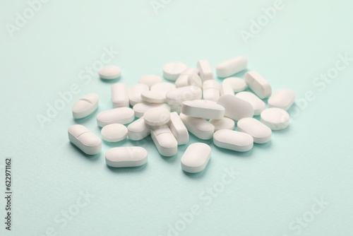 Pile of white pills on mint background