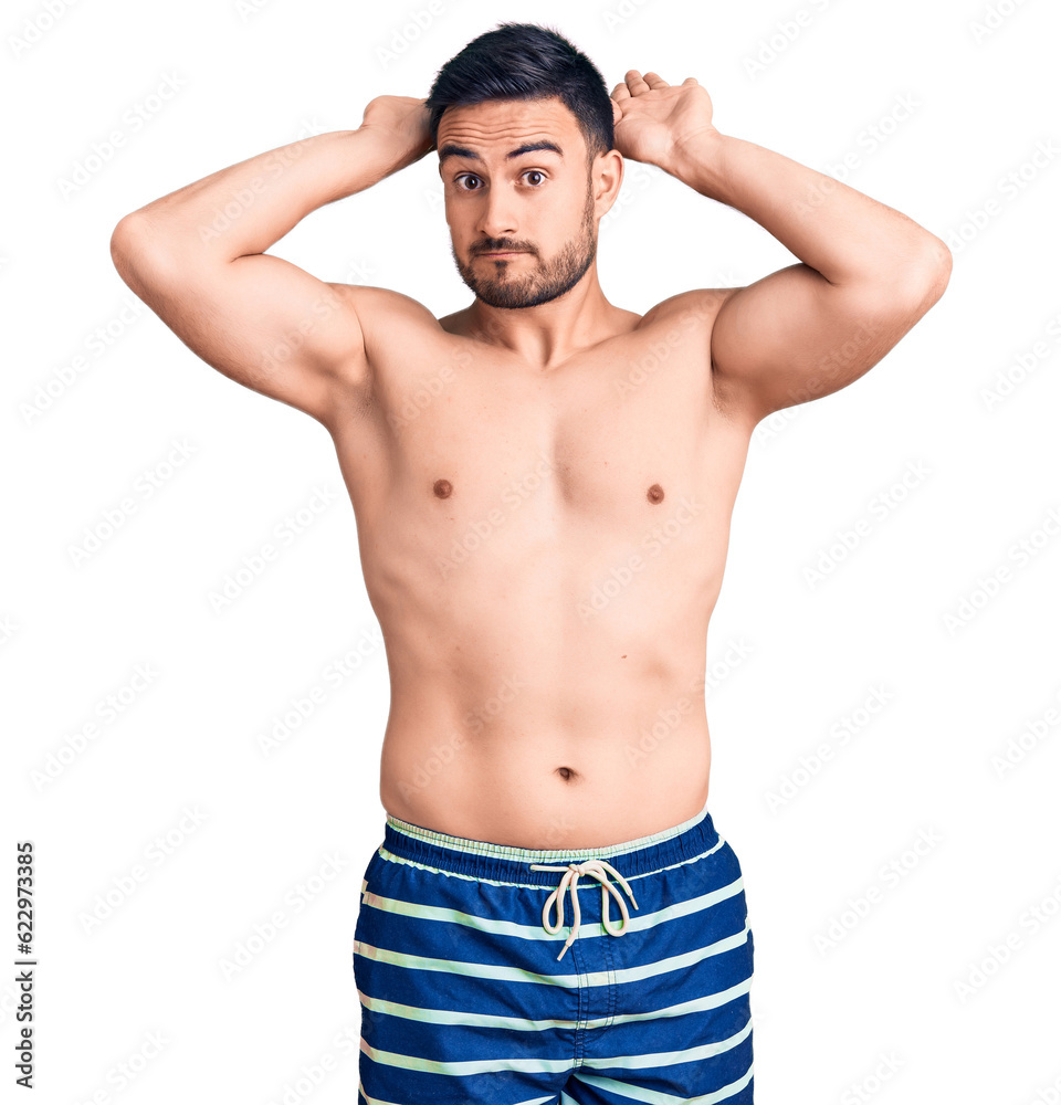 Fototapeta premium Young handsome man wearing swimwear doing bunny ears gesture with hands palms looking cynical and skeptical. easter rabbit concept.